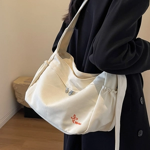 Large beige canvas tote bag with orange embroidery and wide shoulder strap