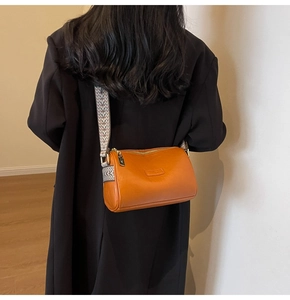 Detail of orange faux leather crossbody bag with geometric woven wide shoulder strap