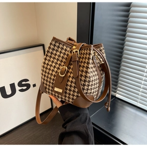 Close-up of retro houndstooth bucket bag with leather strap and metal buckle detail