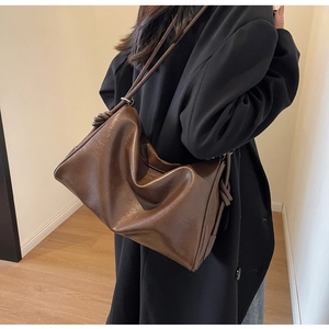 Detail of a large brown vintage shoulder bag with knot design worn by a model
