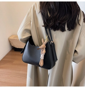 Detail of black leather hobo bag with fashion bag text and a cute bunny pendant