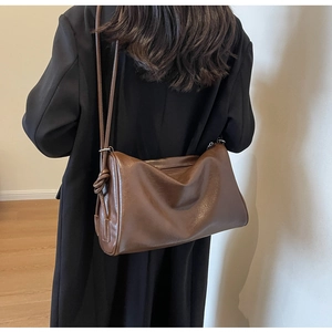 Detail of dark brown leather shoulder bag featuring a unique side knot and adjustable strap