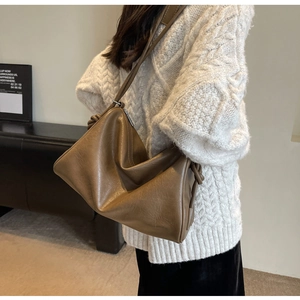 Side view of large brown PU leather shoulder bag with decorative knotted strap detail