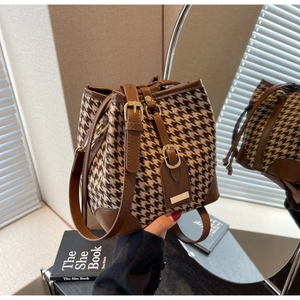 Detail of houndstooth fabric texture and brown leather trim on the bucket bag