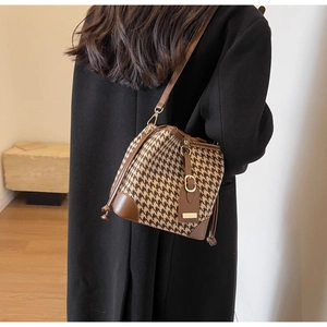 Detail of vintage houndstooth bucket bag with premium brown leather trim and golden buckle