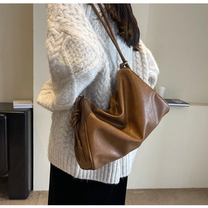 Detail of dark brown leather Boston bag with decorative knot and slouchy commuting style