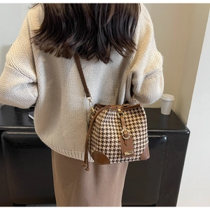 Detail of retro houndstooth bucket bag with leather drawstring on shoulder of a model