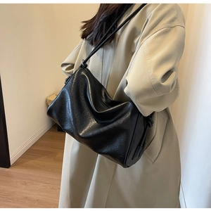 Detail view of a large black faux leather shoulder bag with vintage crinkled texture