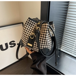 Detail of black and white houndstooth bucket bag with leather trim and gold hardware