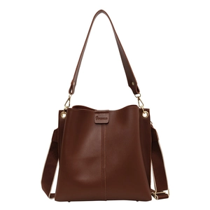 Deep brown leather bucket bag with wide woven shoulder strap and gold hardware