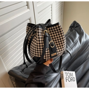 Detail of houndstooth bucket bag with black leather trim and drawstring closure