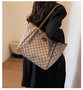 Detail of a large canvas tote bag with geometric print and leather straps on model