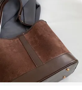 Close-up of brown suede tote bag with leather bottom and gold protective metal feet