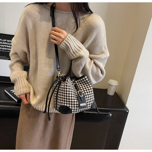 Detail of houndstooth bucket bag with leather trim and drawstring in an elegant setting