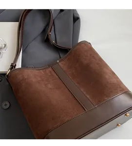 Detail view of large dark brown tote bag with suede texture and metal bottom studs