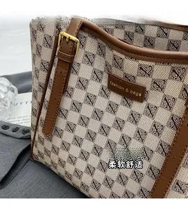 Detail of checkered tote bag fabric and leather handle with golden buckle finish
