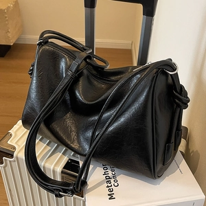 Black glossy Boston bag with large capacity and silver zippers on a white suitcase