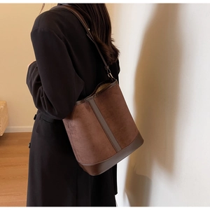 Detailed side view of a large brown suede bucket bag worn as a shoulder bag