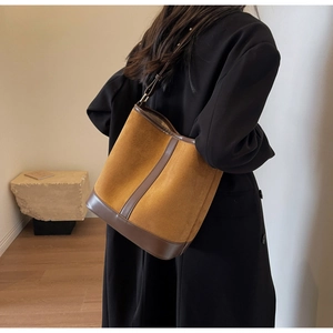 Detailed view of a retro brown bucket bag on a model wearing a classic black coat
