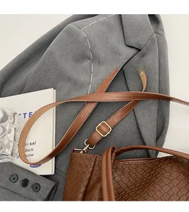 Detail of adjustable leather strap and gold buckle on a brown crocodile texture tote bag