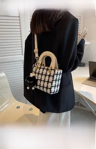 Dettaglio della borsa a mano in tweed a scacchi con tracolla crema e ciondolo di peluche