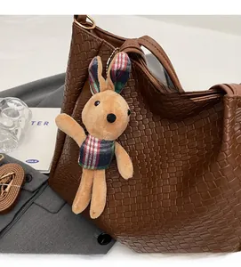 Brown woven tote bag detail showing large capacity, plush rabbit charm, and shoulder strap