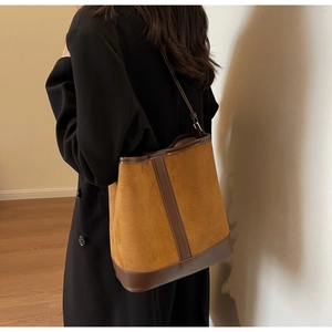 Detail of caramel brown suede bucket bag showing contrast leather textures and stitching