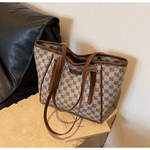 Detail view of large tote bag featuring geometric print and brown leather handles on stone