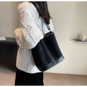 Side view of large black bucket bag showing suede and leather textures on a model