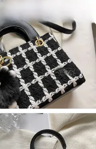 Dettaglio della borsa a mano in tweed a scacchi con hardware oro e pompon nero