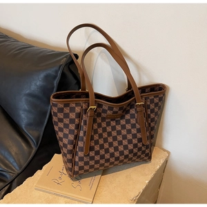 Detailed close-up of brown checkered tote bag with leather straps and metal hardware