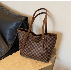 Detailed shot of brown checkered tote bag with leather straps and golden buckles