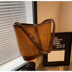 Detail of a large capacity bucket bag featuring brown suede and leather patchwork material