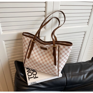 Detail of checkered tote bag with brown leather handles on a leather sofa
