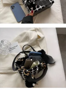 Dettaglio della borsa a quadri capiente con pompon nero e confronto dimensioni smartphone