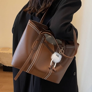 Brown large capacity leather tote bag with white stitching and plush charm decoration