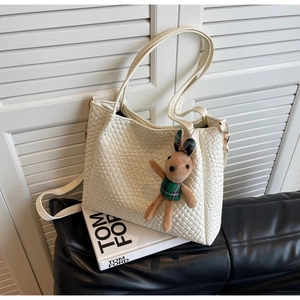 Close-up of cream woven tote bag with cute rabbit charm and dual carrying straps