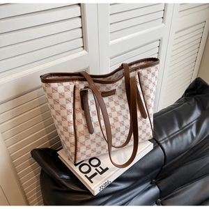 Close-up of checkered tote bag with fashion & bags metal plaque and brown leather straps