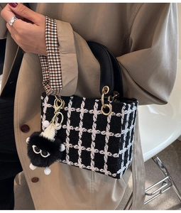 Dettaglio borsa a mano in tweed a scacchi bianco e nero con ciondolo in peluche