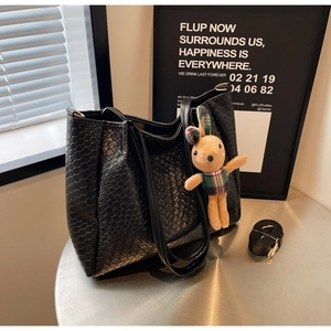 Detail of black woven tote bag with brown plush bunny charm and adjustable strap