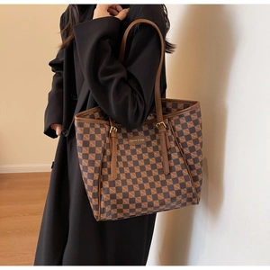 Detail of checkered tote bag showing adjustable gold buckle and smooth leather handle
