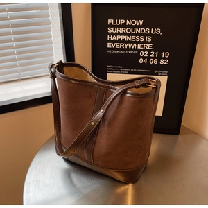Detail of vintage matte brown bucket bag with adjustable leather strap on metal surface