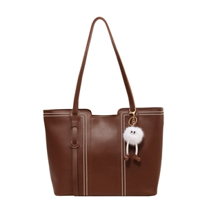 Brown faux leather tote bag with white contrast stitching and a white plush keychain charm