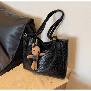 Detail of black woven texture tote bag with a cute brown bunny plush charm accessory