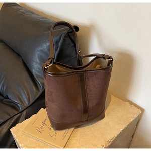 Detail of large brown suede bucket bag with leather base on stone pedestal