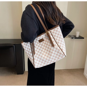 Detail view of large plaid tote bag with brown leather trim and fashion engraving