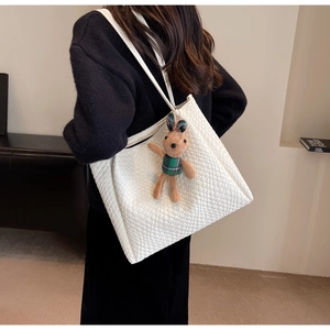 Detail of white woven tote bag texture with a cute plush rabbit charm on the side