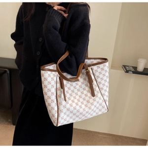 Detail of checkered tote bag with brown leather strap and elegant gold hardware