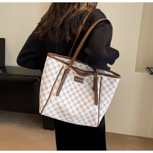 Detail of white and brown checkered tote bag with leather straps and gold buckle accents