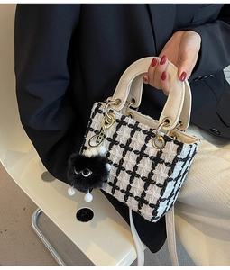 Dettaglio della borsa a mano in tweed bianco e nero con finiture dorate e ciondolo
